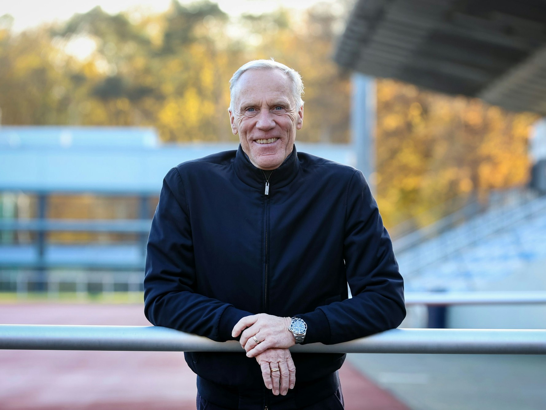 Ingo Froböse lehnt sich im Stadion der Sporthochschule Köln über eine Barriere und schaut in die Kamera.