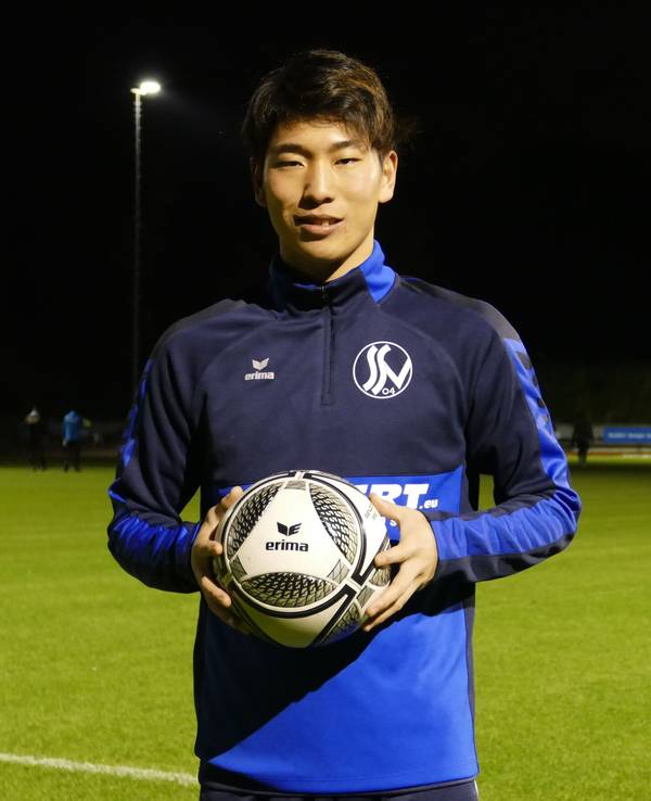 Kaito Asano vom Siegburger SV 04 steht mit einem Fußball in der Hand am Spielfeld.