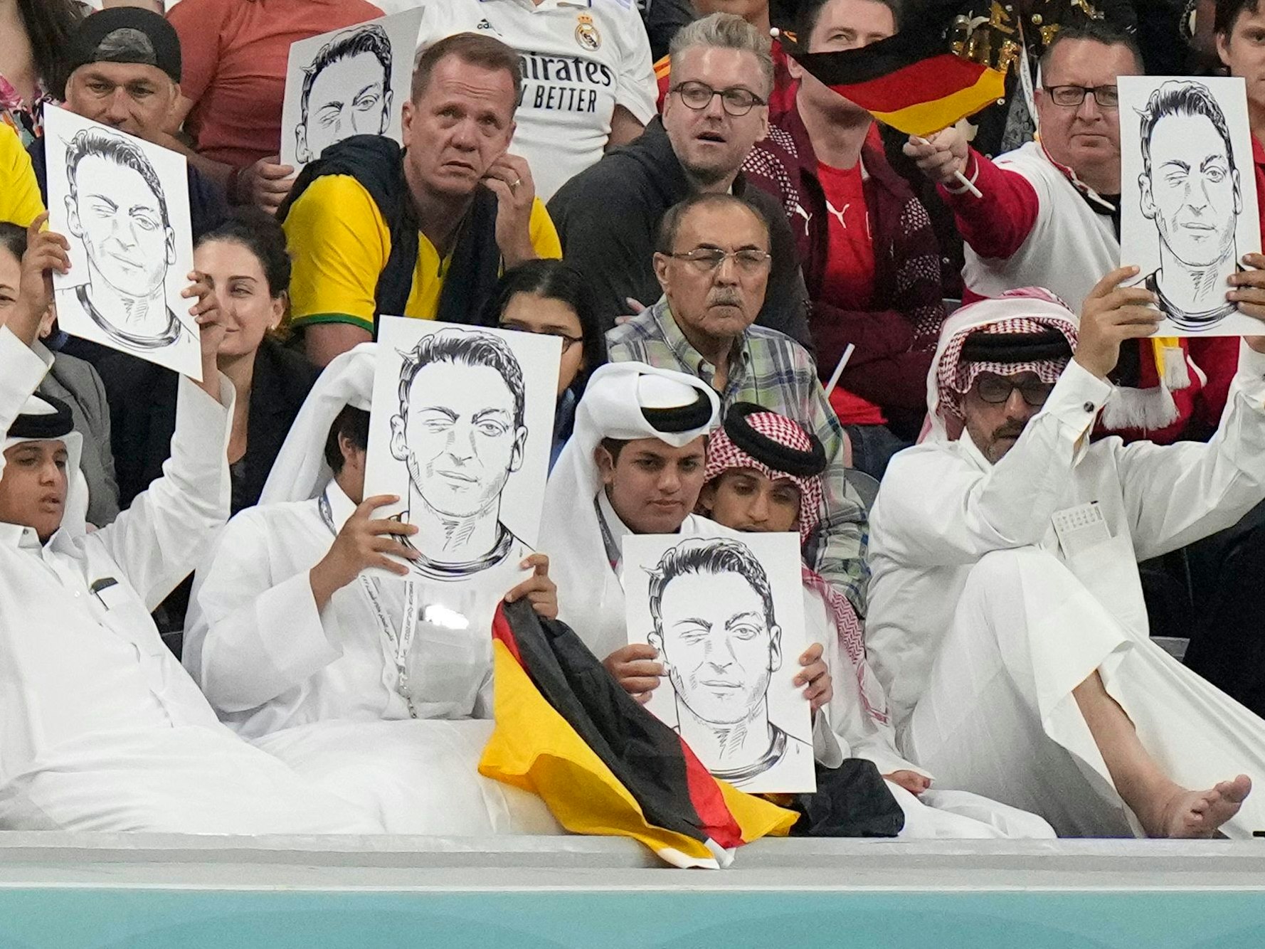 Zuschauer im Al-Bait Stadion halten Bilder von Deutschlands ehemaligem Nationalspieler Mesut Özil in die Höhe.