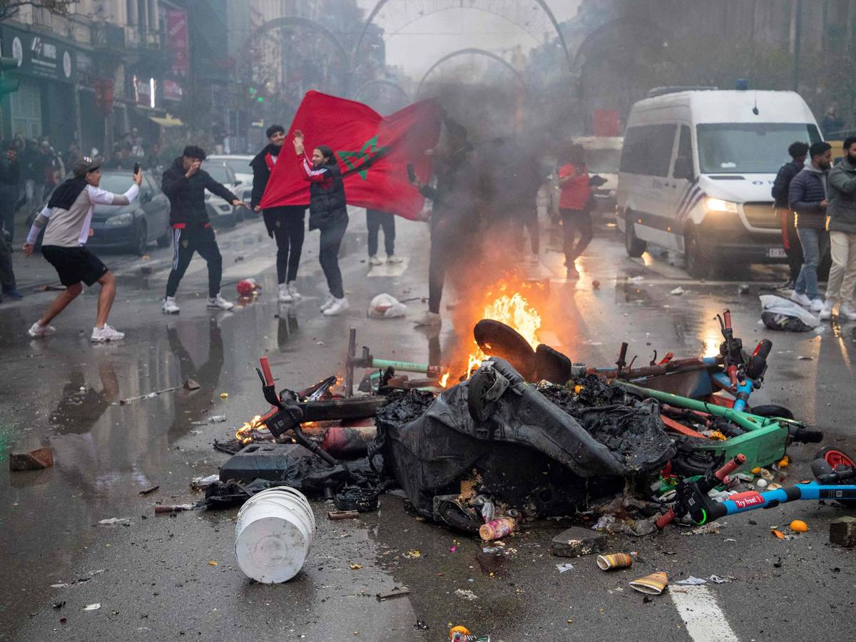 Fußball-Fans stehen in Brüssel neben einer brennenden Straßen-Barrikade.