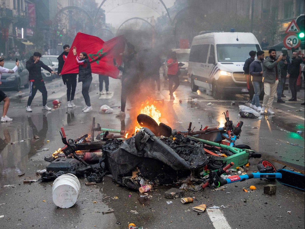Fußball-Fans stehen in Brüssel neben einer brennenden Straßen-Barrikade.