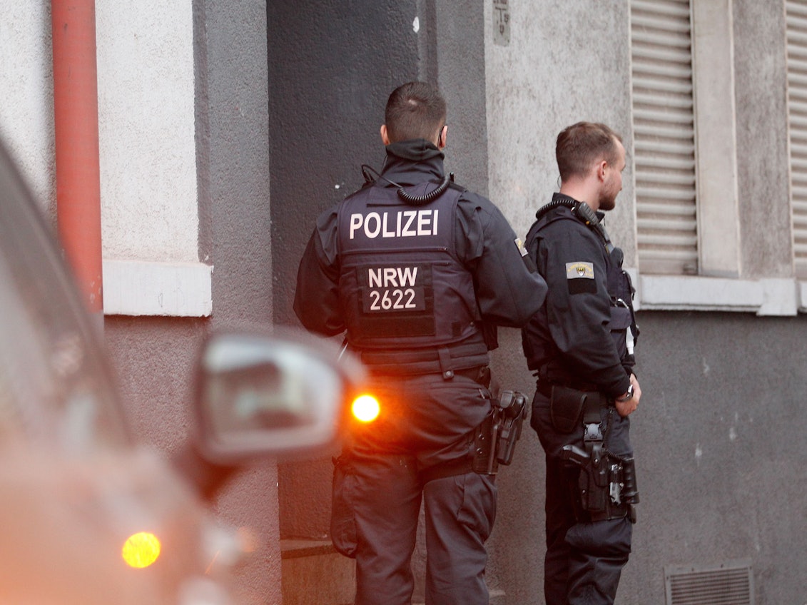 Polizisten stehen vor einem Haus, in dem sie eine Wohnung durchsucht haben.