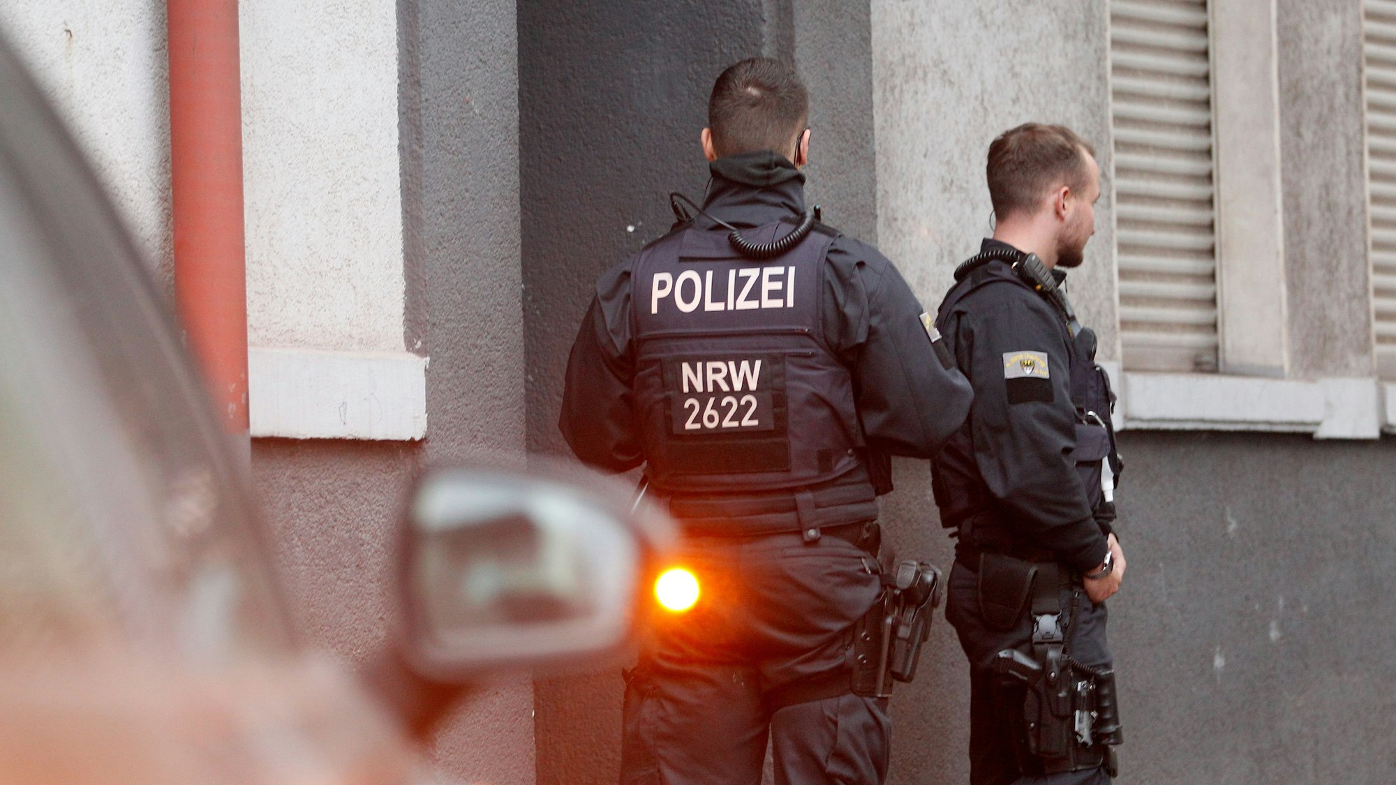 Polizisten stehen vor einem Haus, in dem sie eine Wohnung durchsucht haben.