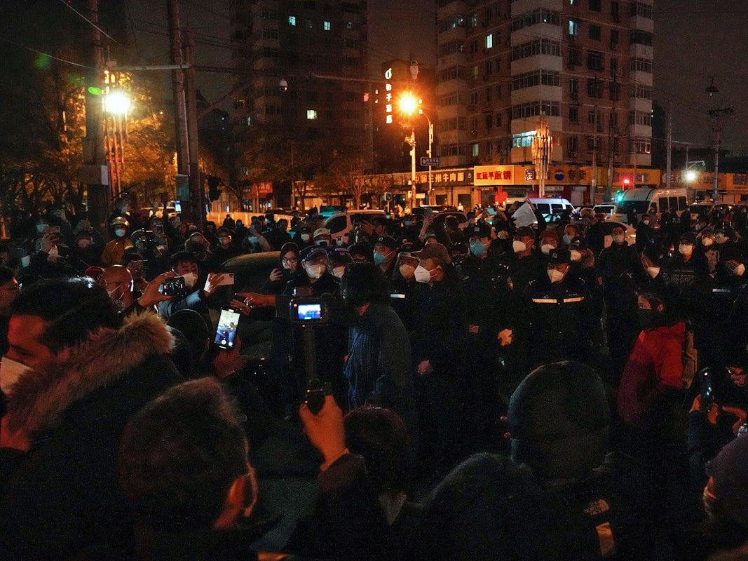 Demonstrierende stoßen mit Polizisten während einer Demonstration zusammen. In China hat die strenge Corona-Politik am Wochenende zu den größten Protesten seit Jahrzehnten geführt.