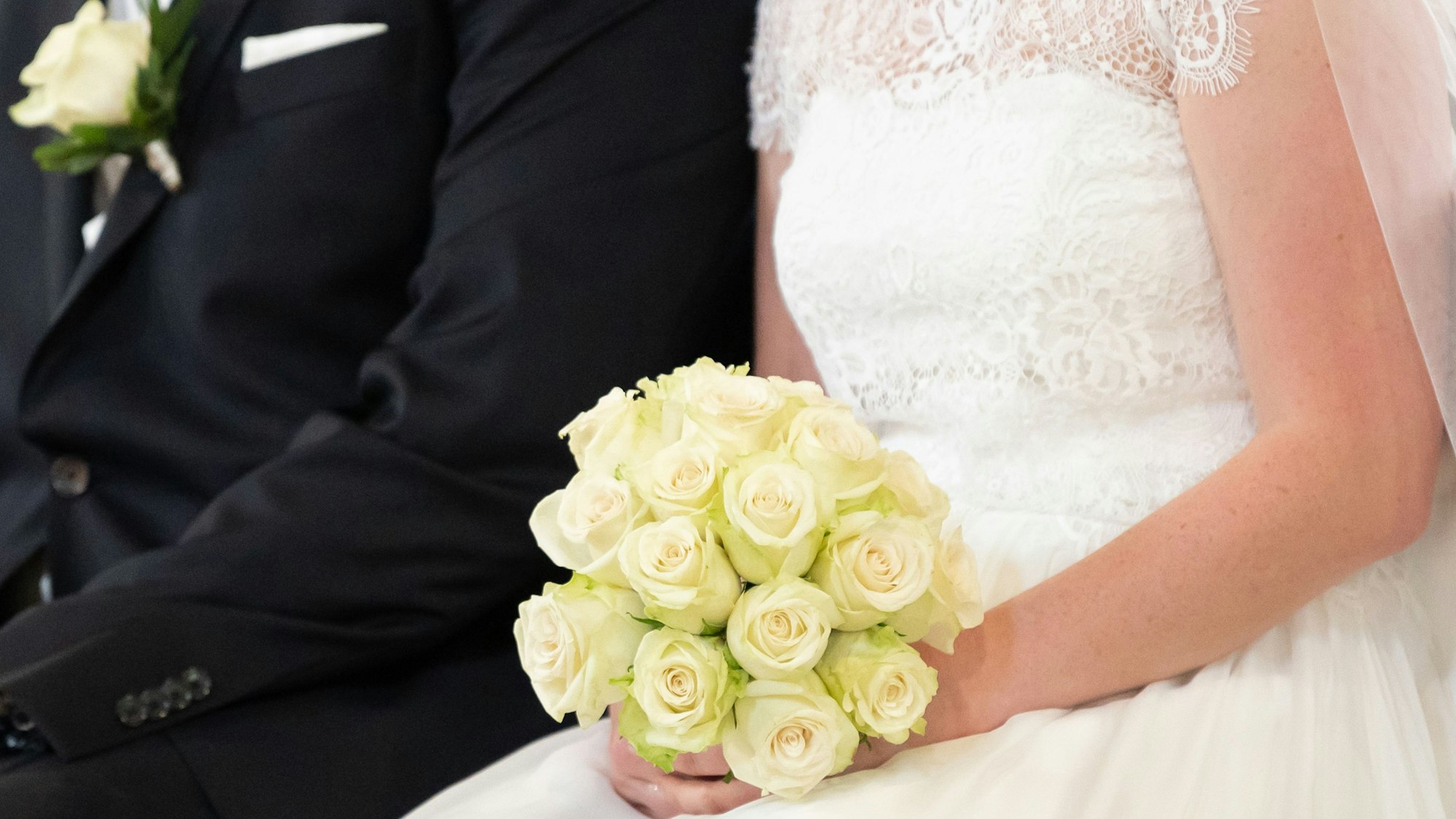 Ein Brautpaar sitzt während ihrer Trauung in der Kirche.