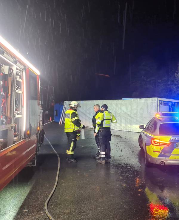 Einsatzkräfte von Polizei und Feuerwehr stehen am Unfallort auf der A61