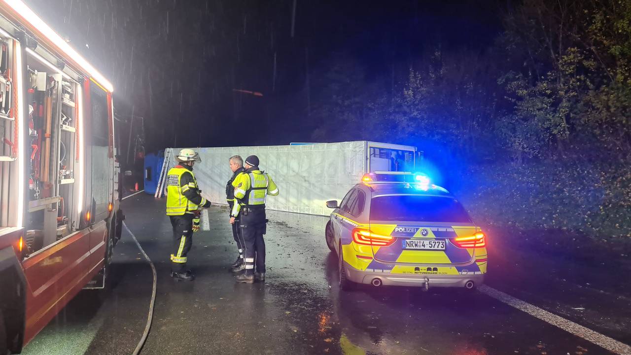 Einsatzkräfte von Polizei und Feuerwehr stehen am Unfallort auf der A61