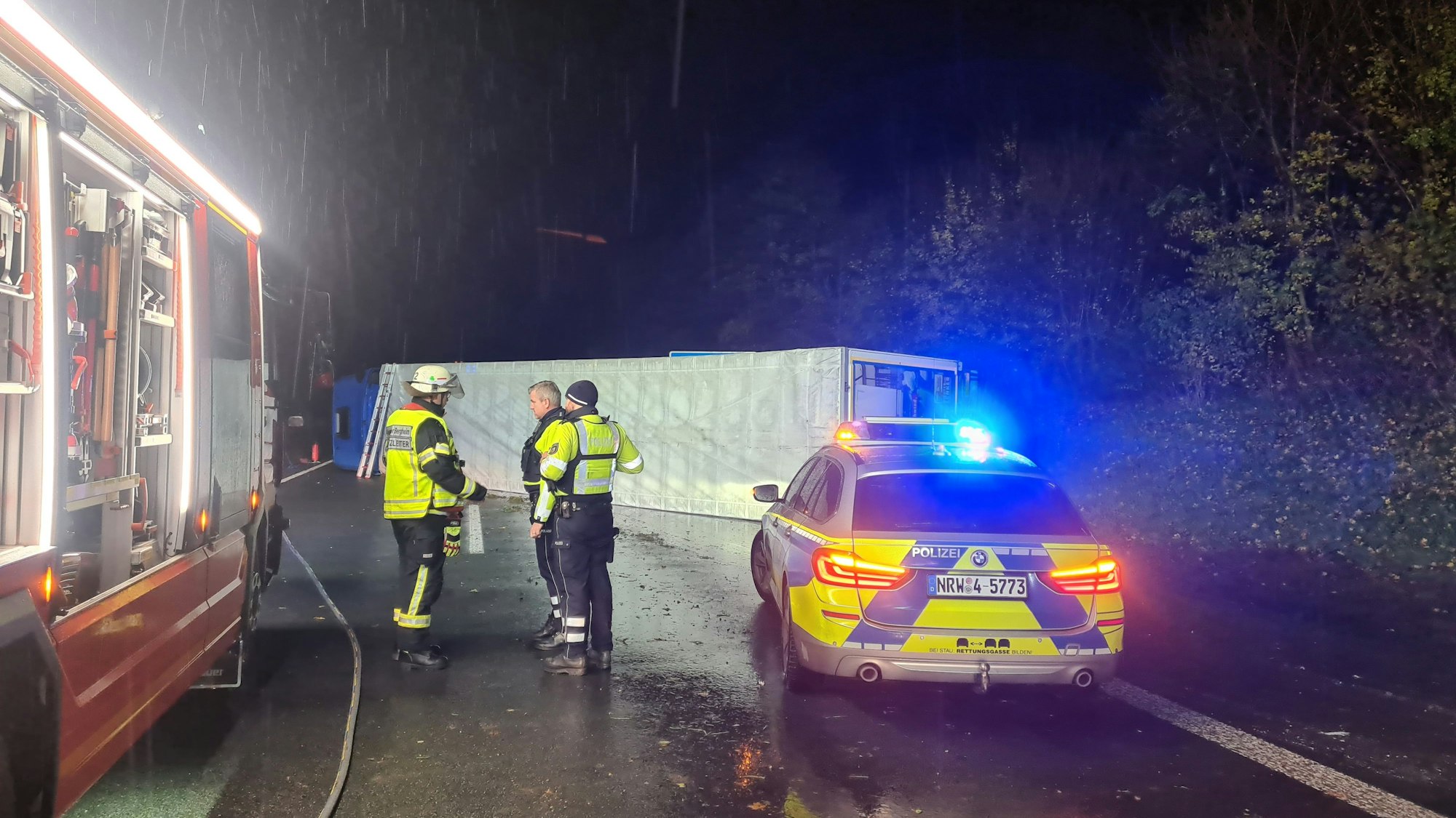 Einsatzkräfte von Polizei und Feuerwehr stehen am Unfallort auf der A61