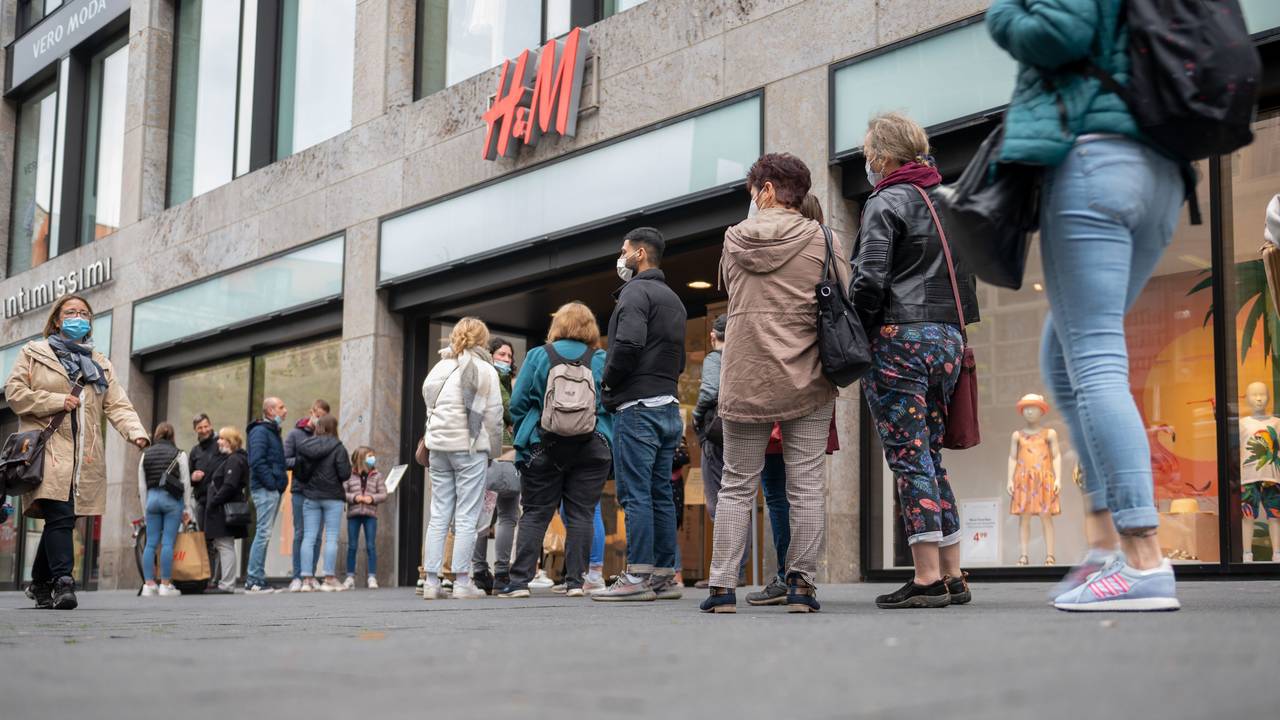 Kundinnen und Kunden stehen in einer Schlange vor einer H&M-Filiale.