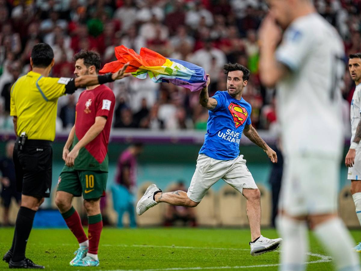 Ein Flitzer mit Regenbogenfahne sorgte für eine Unterbrechung des WM-Spiels zwischen Portugal (hier mit Bernardo Silva im roten Trikot) und Portugal (rechts mit Matias Vecino) am 28. November 2022. Links: Schiedsrichter Alireza Faghani, der die Fahne später aufhob.