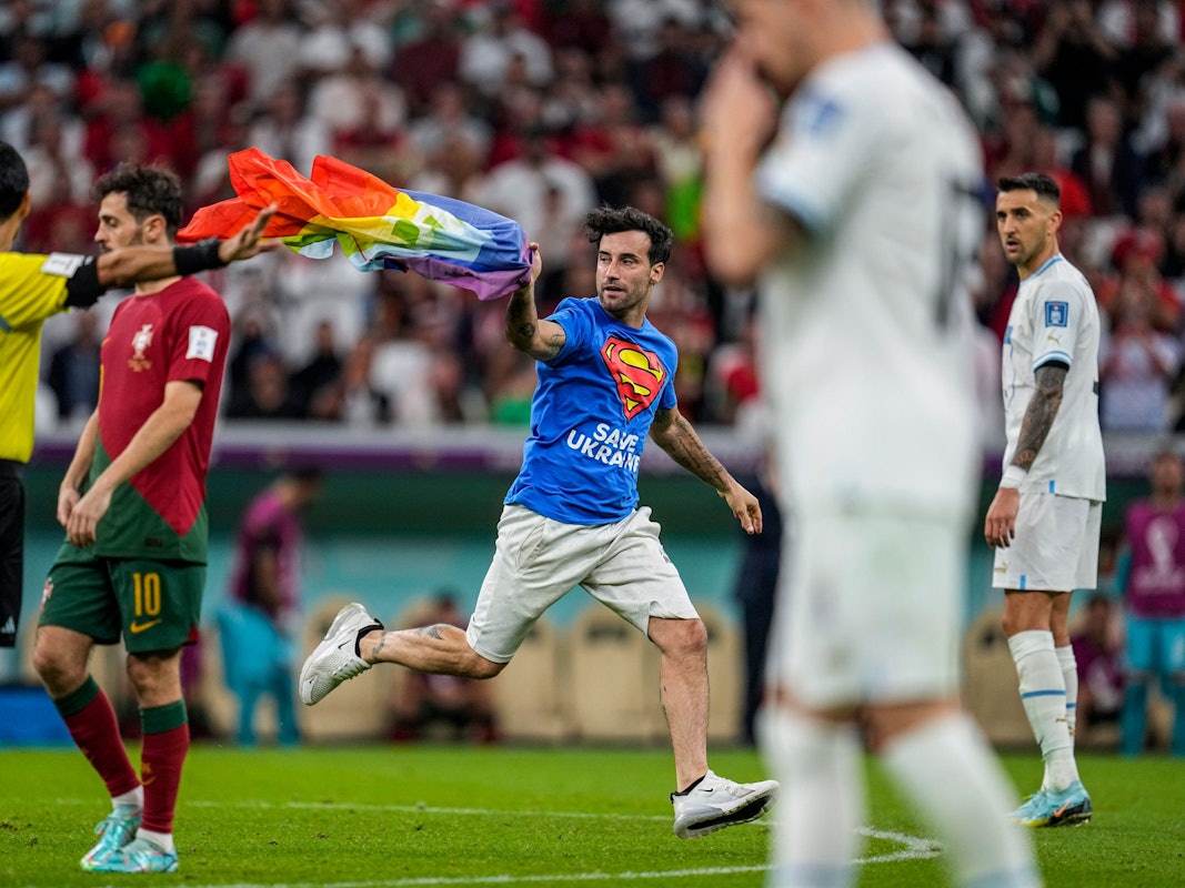 Ein Flitzer mit Regenbogenfahne sorgte für eine Unterbrechung des WM-Spiels zwischen Portugal (hier mit Bernardo Silva im roten Trikot) und Portugal (rechts mit Matias Vecino) am 28. November 2022. Links: Schiedsrichter Alireza Faghani, der die Fahne später aufhob.