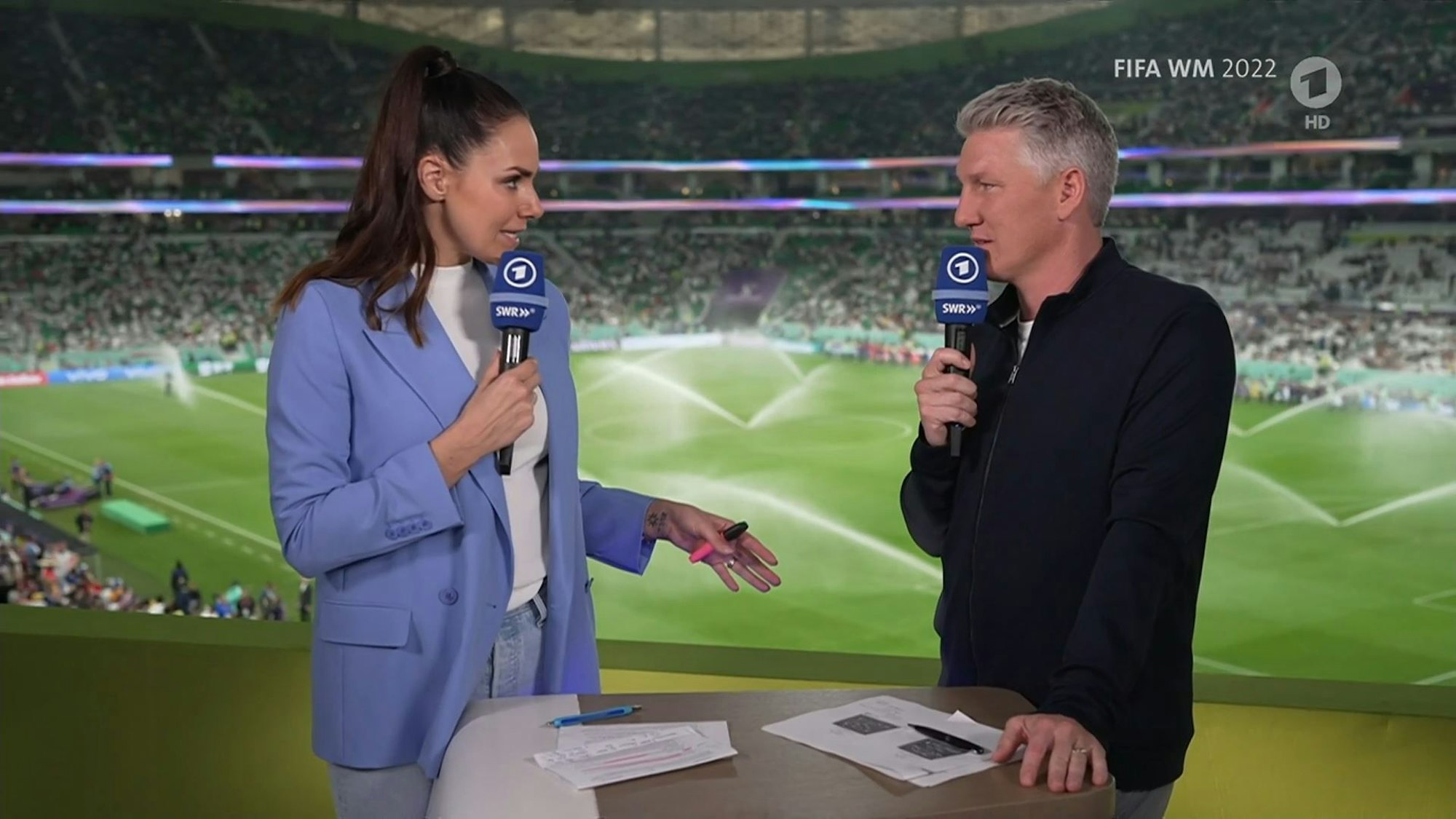 Bei der ARD-Übertragung zum Spiel zwischen den USA und dem Iran sprechen Esther Sedlaczek und Bastian Schweinsteiger im Stadion.