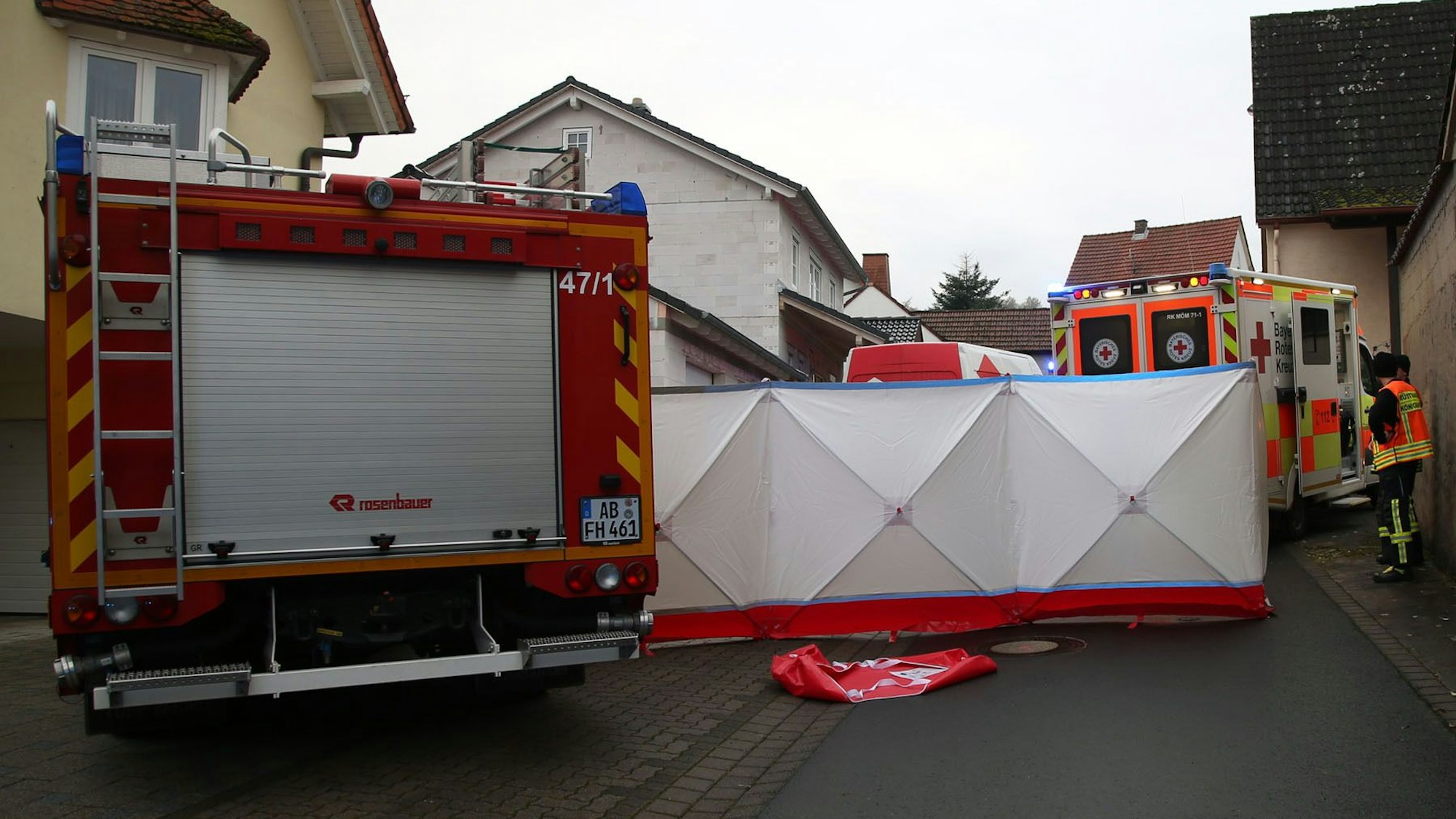 Einsatzkräfte von Feuerwehr und Rettungsdienst bei einem Unfall, die Unfallstelle wurde mit einem Sichtschutz verdeckt.