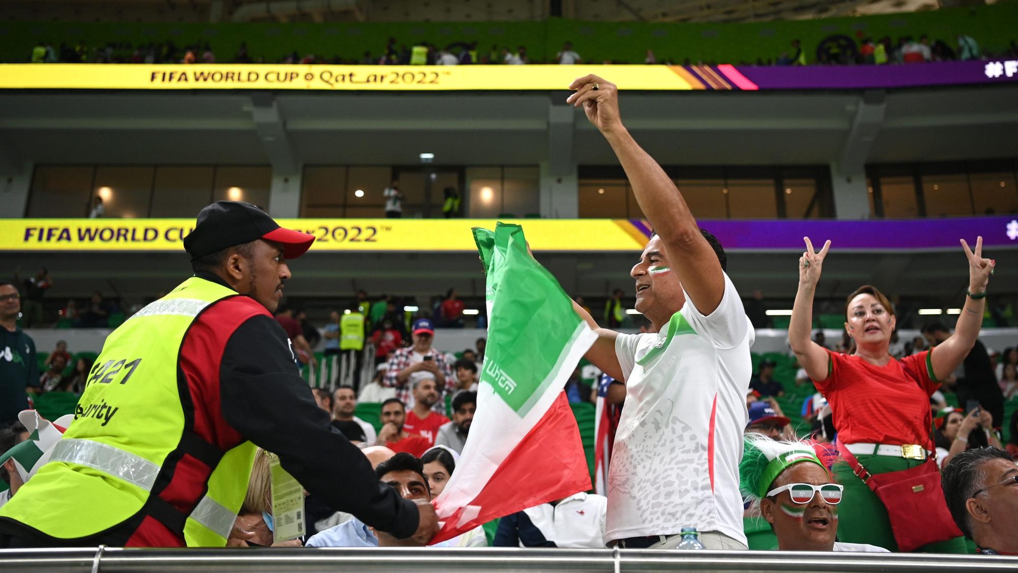 Ein Security-Mitarbeiter konfisziert bei der WM 2022 in Katar eine Flagge des Iran, auf der das Symbol der Islamischen Republik ausgeschnitten ist.