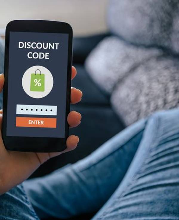 Hand hält Smartphone hoch mit Coupon auf dem Screen.