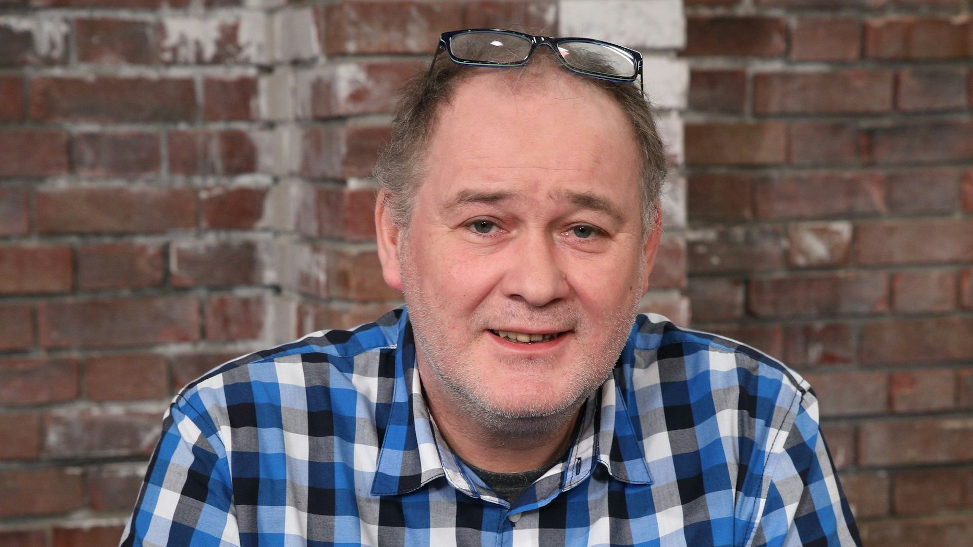 Walter Lehnertz lacht bei einem Fototermin in einem blauen, kariertem Hemd in die Kamera.