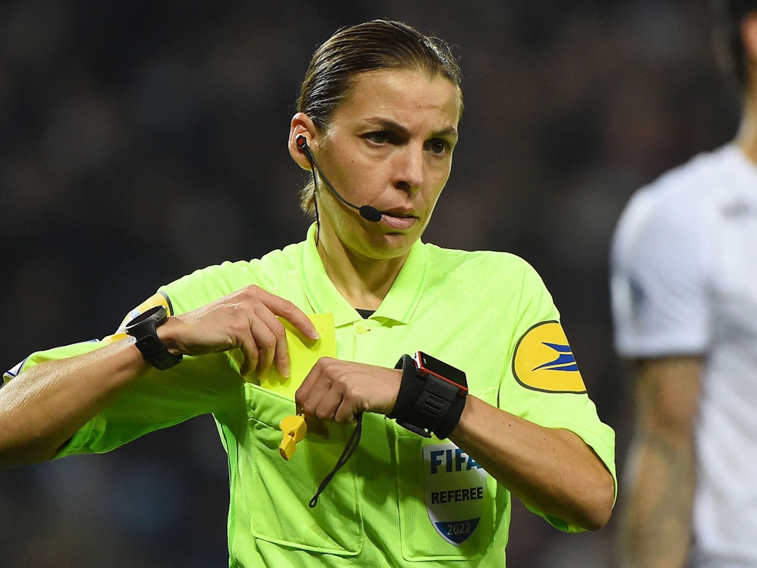 Schiedsrichterin Stéphanie Frappart steckt eine Gelbe Karte in ihre Brusttasche.