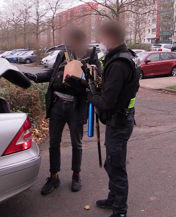 Polizisten verlassen mit beschlagnahmten Gegenständen nach einer Durchsuchung ein Haus.