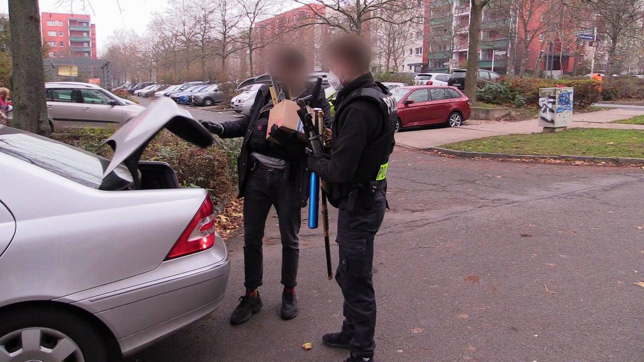 Polizisten verlassen mit beschlagnahmten Gegenständen nach einer Durchsuchung ein Haus.