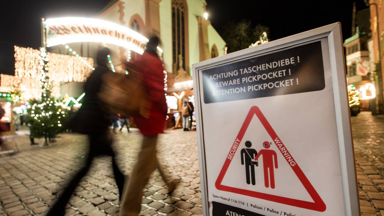 Symbolbild: 27.11.2017, Baden-Württemberg, Freiburg: Menschen gehen über den eröffneten Weihnachtsmarkt. Ein Schild warnt vor Taschendieben.
