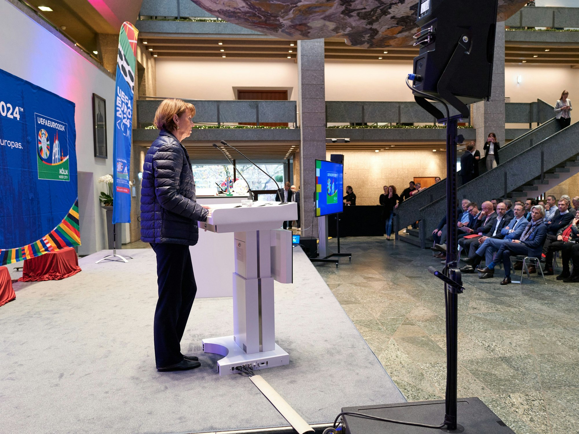 Henriette Reker steht am Rednerpult und hält vor Gästen der UEFA in Köln eine Rede.