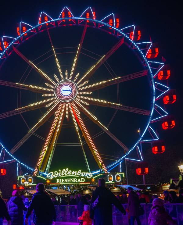 Vor dem Riesenrad auf dem Weihnachtsmarkt beim Roten Rathaus fahren Besucher des Weihnachtsmarkts mit Schlittschuhen auf der Eisfläche.