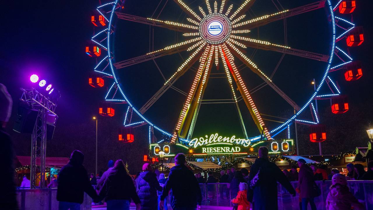 Vor dem Riesenrad auf dem Weihnachtsmarkt beim Roten Rathaus fahren Besucher des Weihnachtsmarkts mit Schlittschuhen auf der Eisfläche.