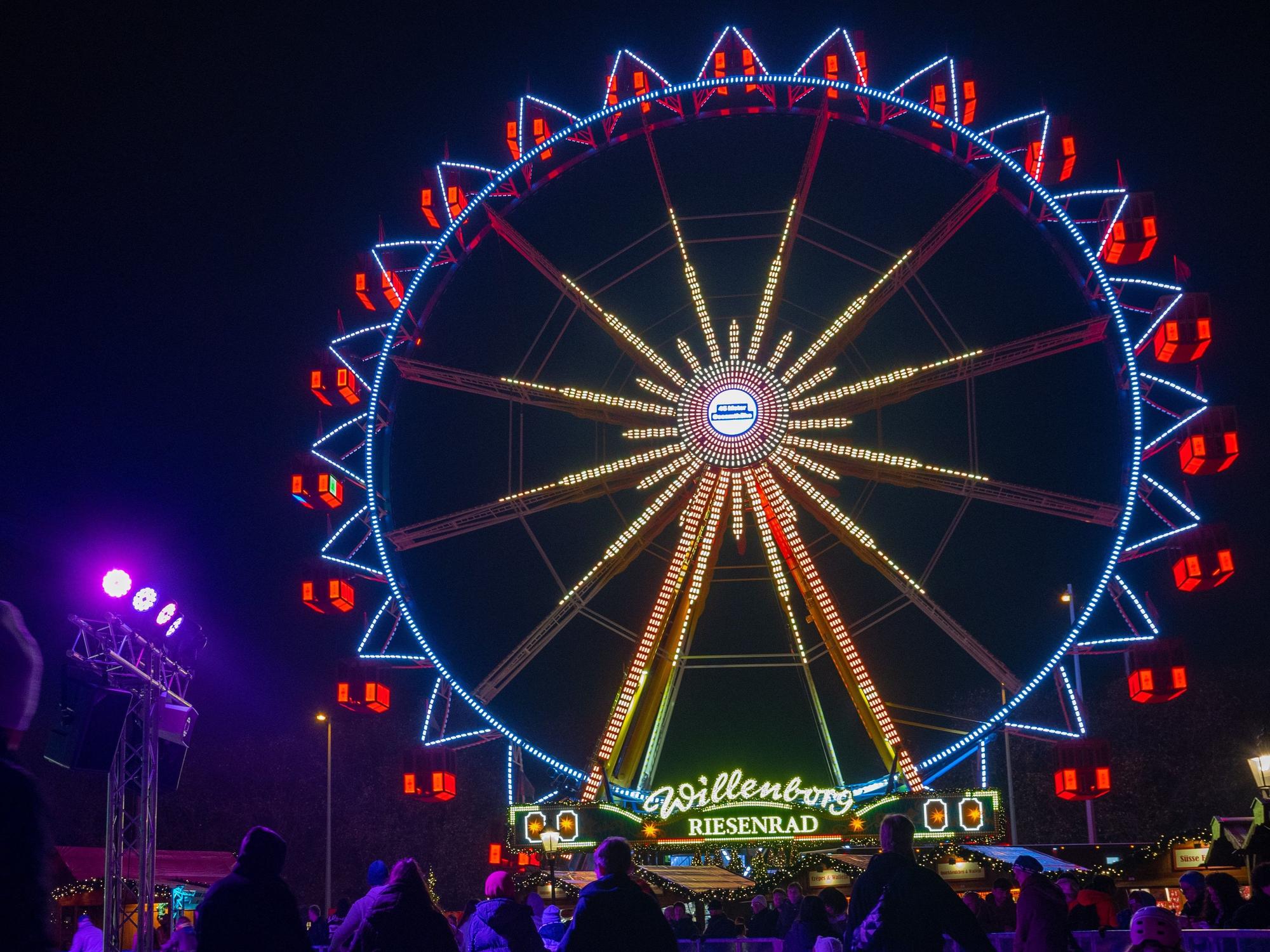 Vor dem Riesenrad auf dem Weihnachtsmarkt beim Roten Rathaus fahren Besucher des Weihnachtsmarkts mit Schlittschuhen auf der Eisfläche.