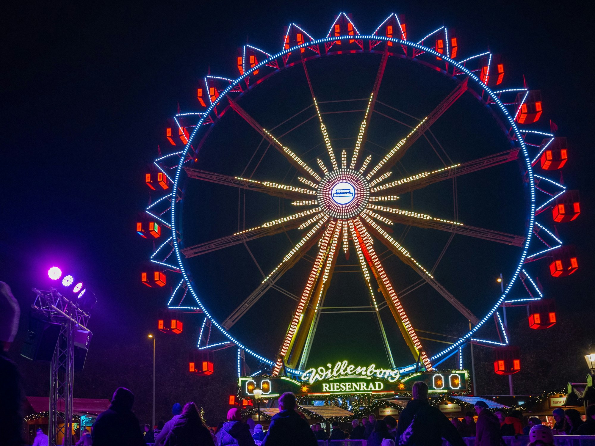 Vor dem Riesenrad auf dem Weihnachtsmarkt beim Roten Rathaus fahren Besucher des Weihnachtsmarkts mit Schlittschuhen auf der Eisfläche.