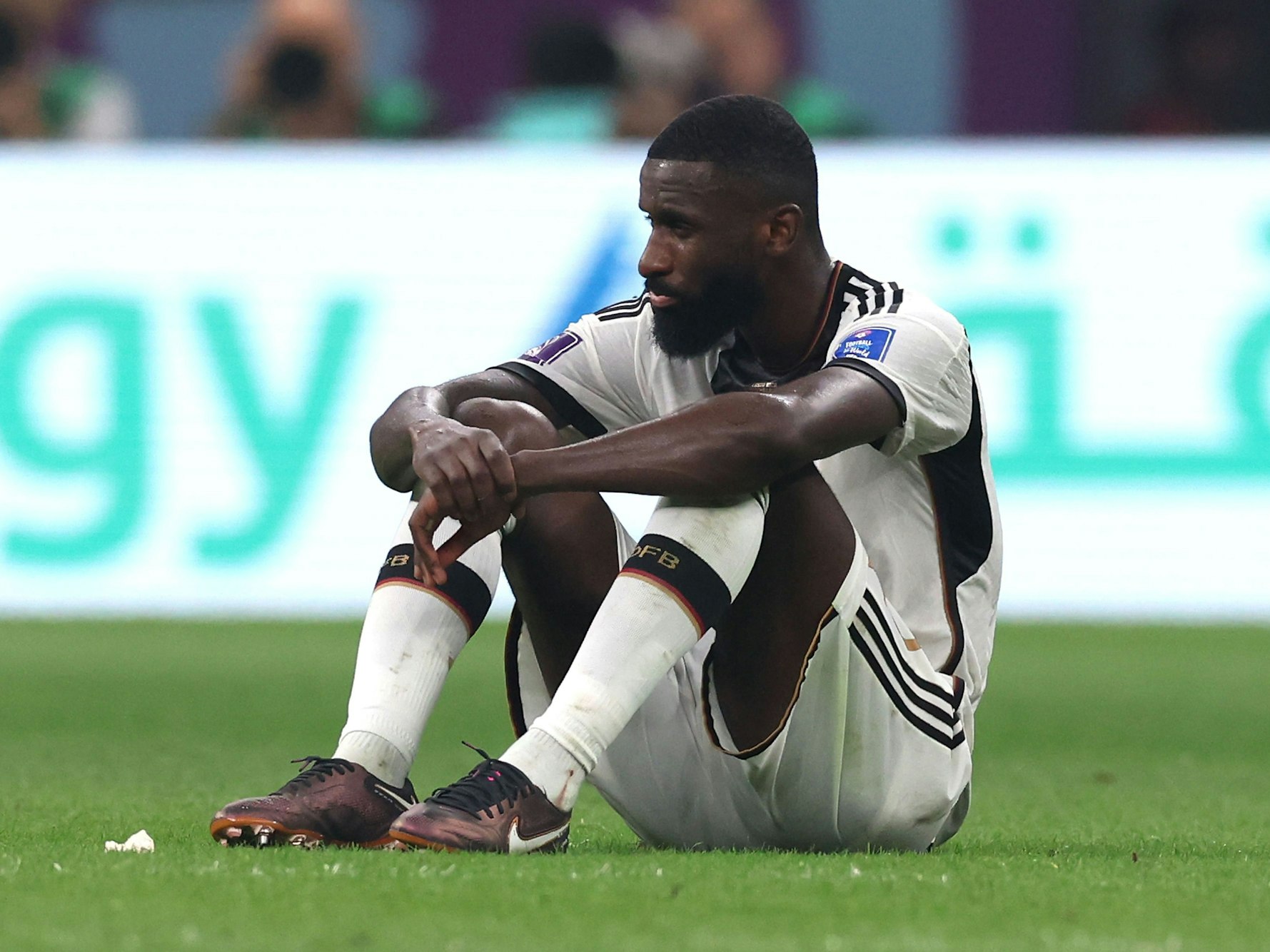 Antonio Rüdiger sitzt frustriert auf dem Rasen des Stadions.