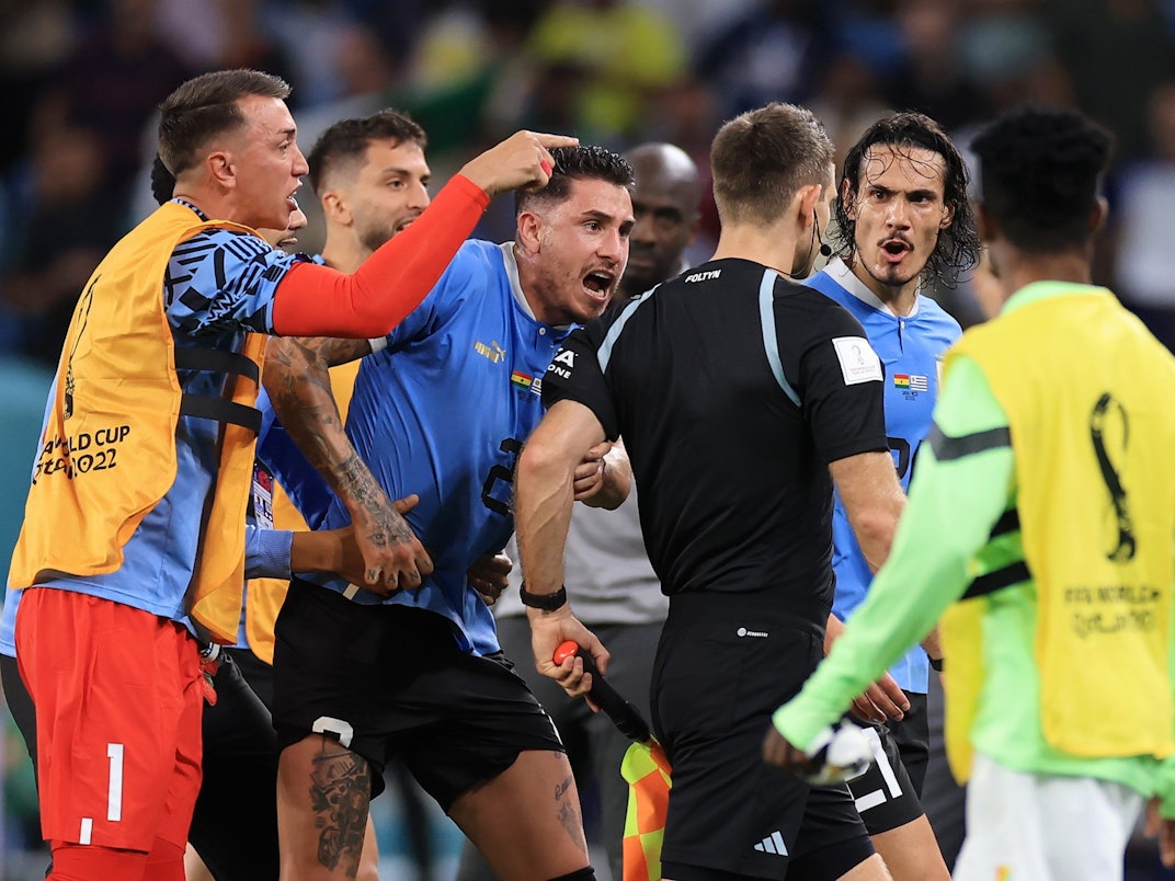 Nationalspieler Uruguays umzingeln den deutschen Schiedsrichter Daniel Siebert nach dem WM-Gruppenspiel gegen Ghana (2:0).