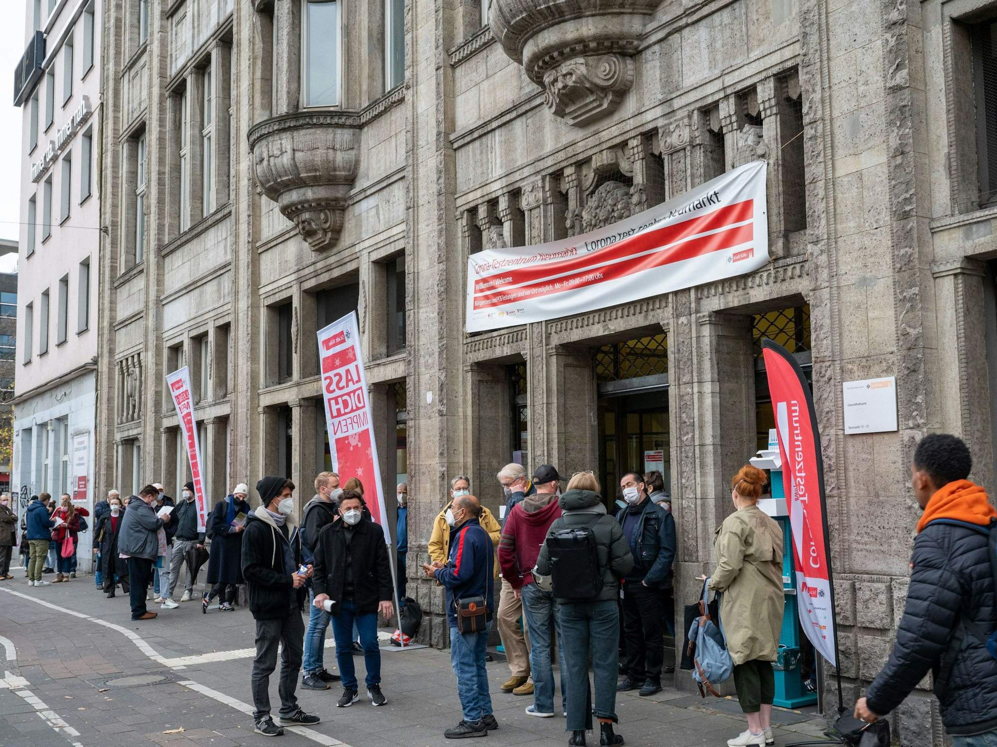 Menschen stehen Schlange vor dem Eingang des Gesundheitsamts in Köln. Hier wollen sie gegen Corona geimpft werden.