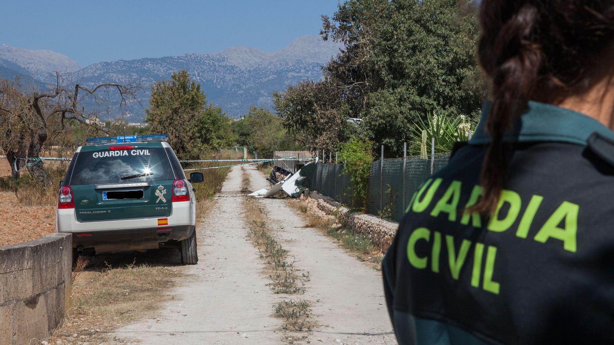 Ein Mitglied der Polizeieinheit „Guardia Civil“ steht nahe einer Absturzstelle, an der nach einer Kollision eines Ultraleichtflugzeugs mit einem Hubschrauber hinter Absperrband Wrackteile liegen.