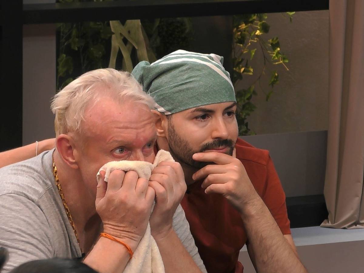Menderes und Rainer schauen gemeinsam die Videobotschaft von Rainers Kindern auf dem TV an. Sie sind sichtlich ergriffen.