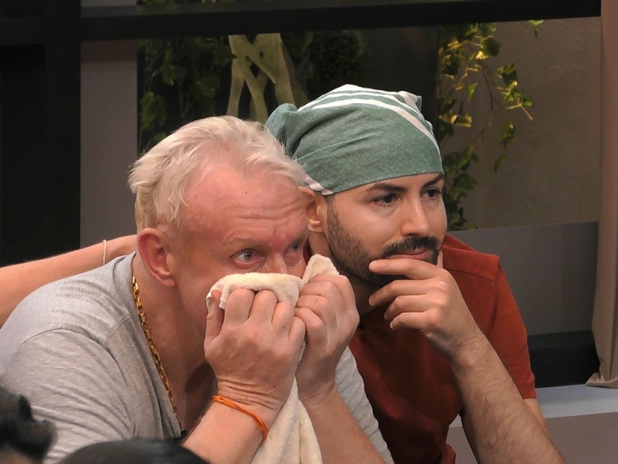 Menderes und Rainer schauen gemeinsam die Videobotschaft von Rainers Kindern auf dem TV an. Sie sind sichtlich ergriffen.