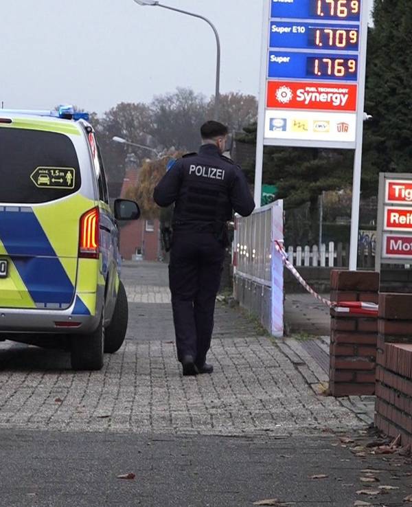 Ein Polizeifahrzeug steht vor einer Tankstelle in Lengerich, daneben steht ein Polizist.