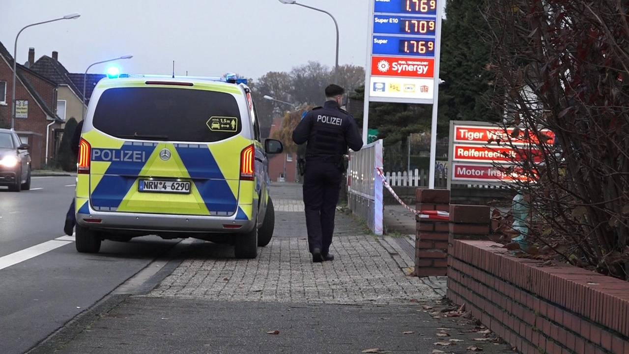 Ein Polizeifahrzeug steht vor einer Tankstelle in Lengerich, daneben steht ein Polizist.
