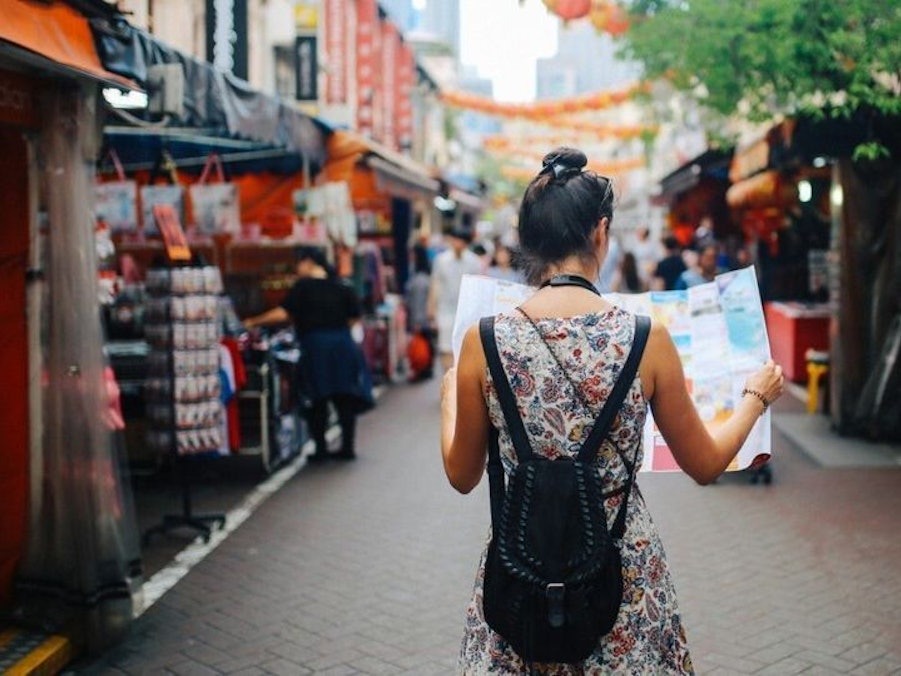 Eine junge Frau liest während einer Reise eine Landkarte.