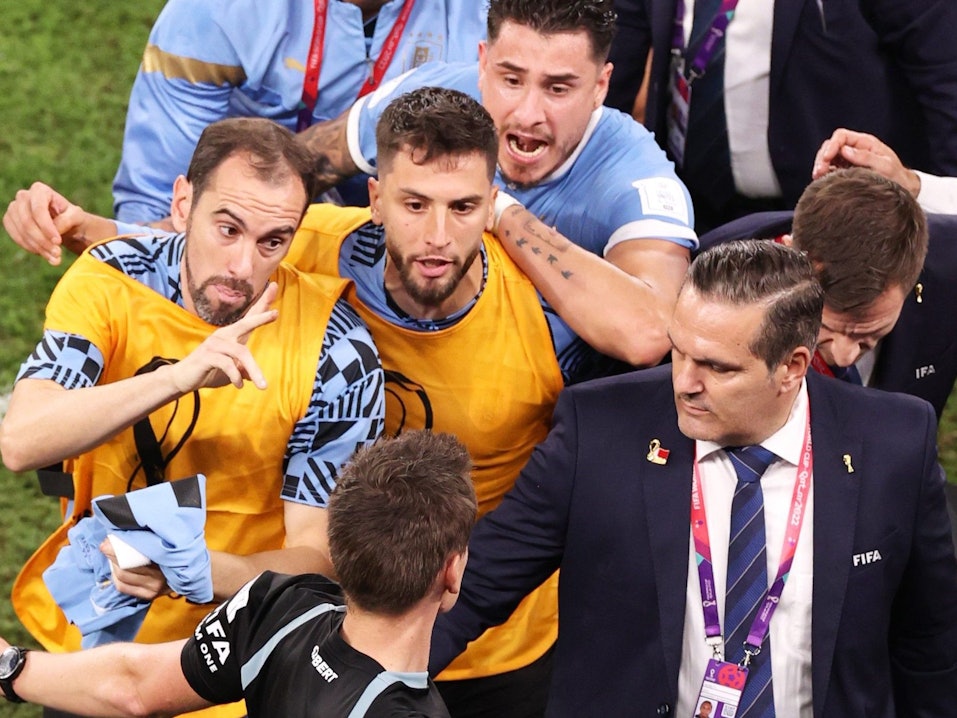 Schiedsrichter Daniel Siebert (unten) wird nach dem WM-Spiel zwischen Uruguay und Ghana von mehreren Spielern der ausgeschiedenen Südamerikaner belagert.