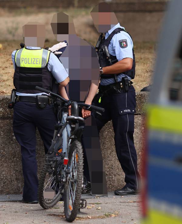 Zwei Einsatzkräfte nehmen einen Mann fest.