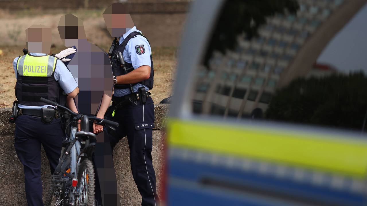 Zwei Einsatzkräfte nehmen einen Mann fest.