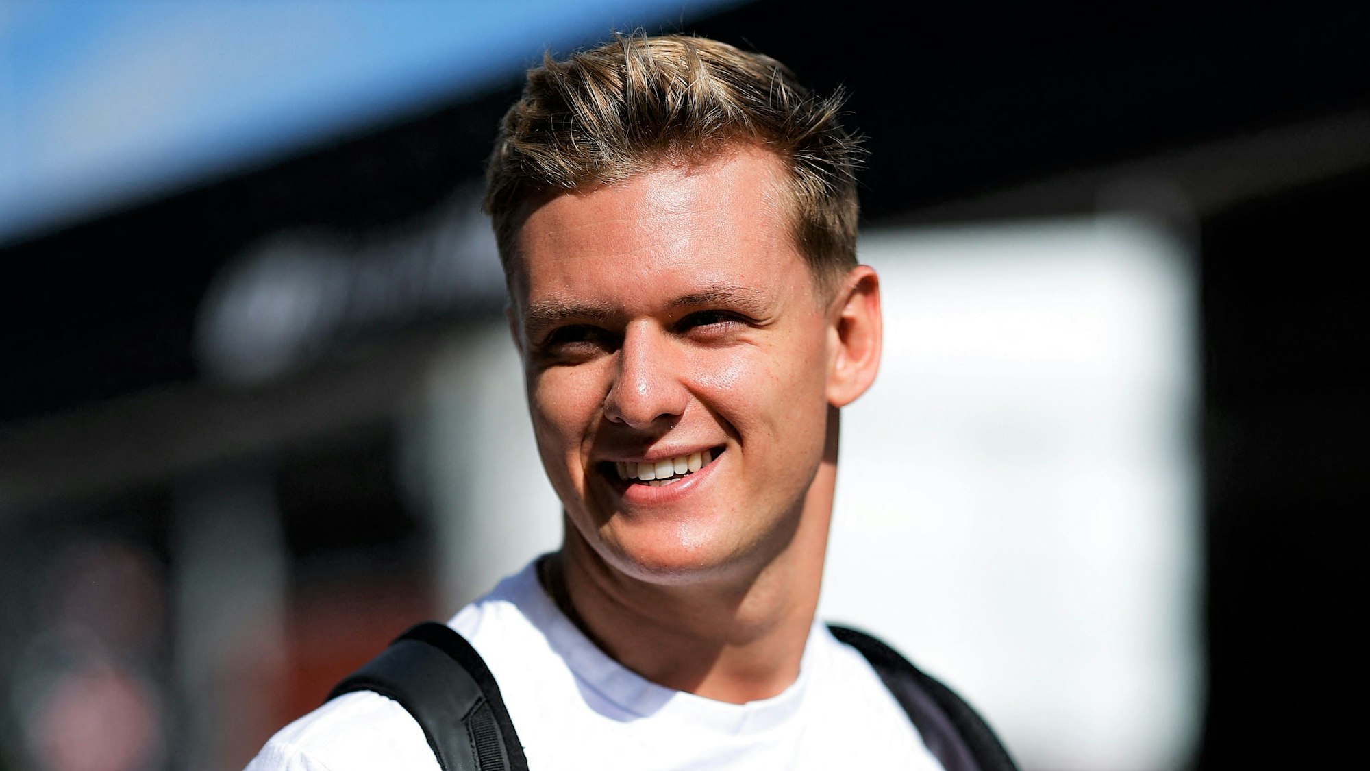 Mick Schumacher geht am Rande des USA-Rennens der Formel 1 in Austin lächelnd durch das Fahrerlager