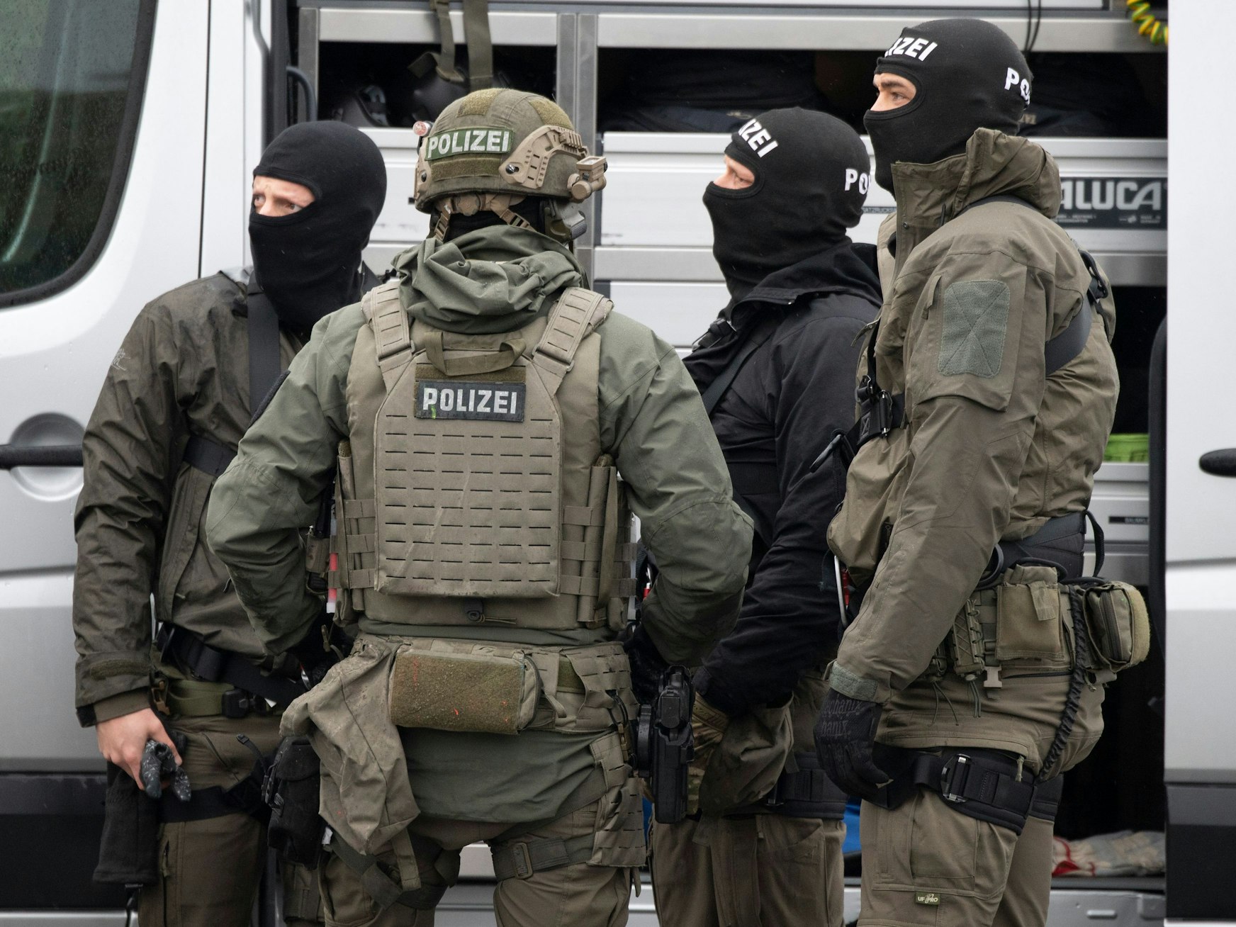 Mitglieder des SEK der Polizei stehen vor einem Einsatzfahrzeug und beraten sich.