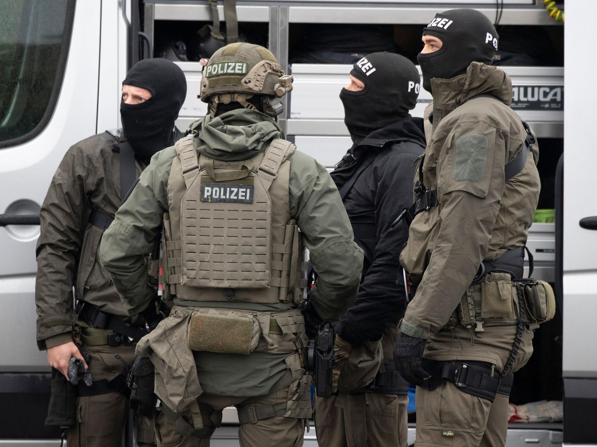 Mitglieder des SEK der Polizei stehen vor einem Einsatzfahrzeug und beraten sich.