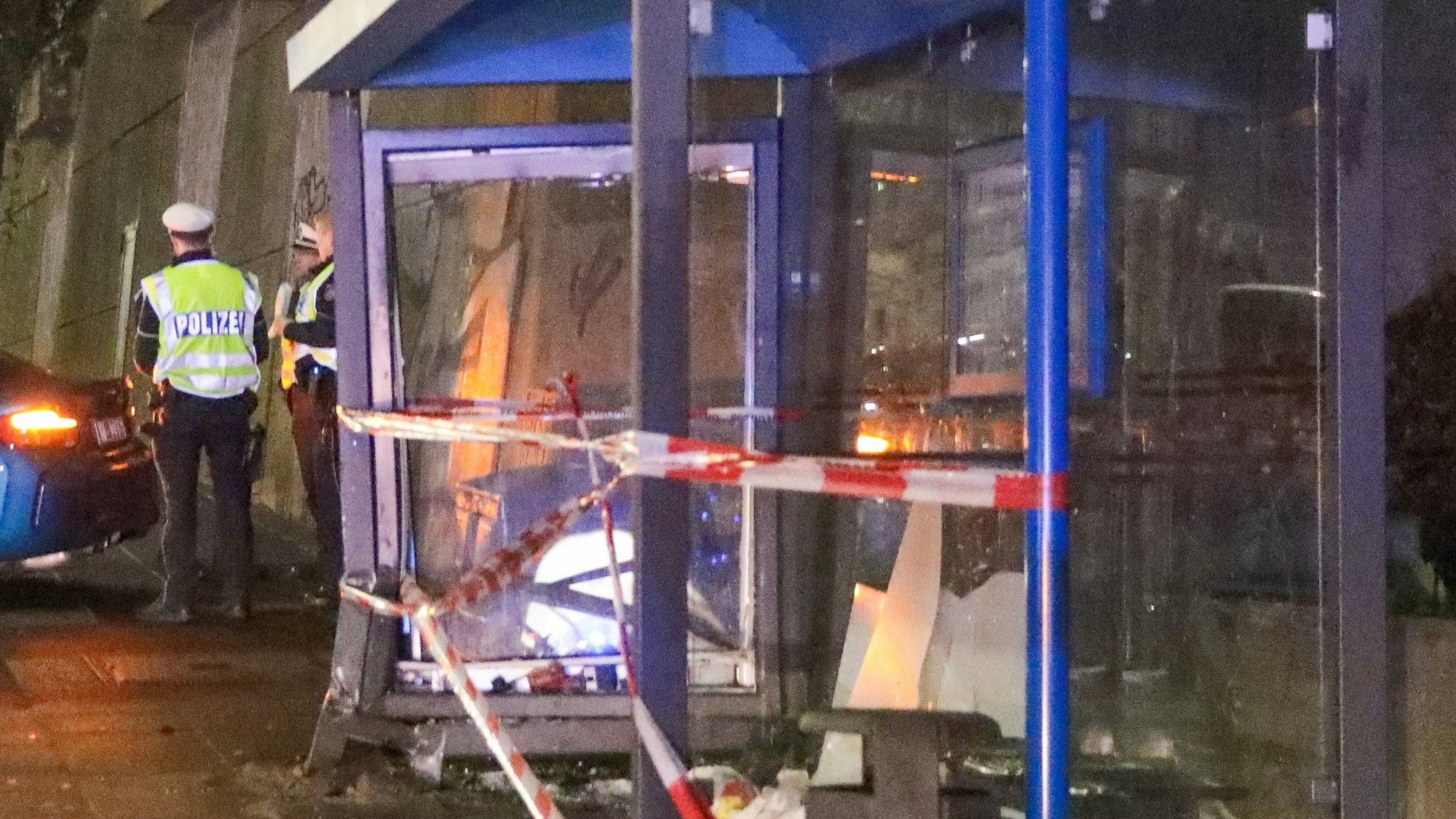 Einsatzkräfte der Polizei ermitteln an einer Bushaltestelle.