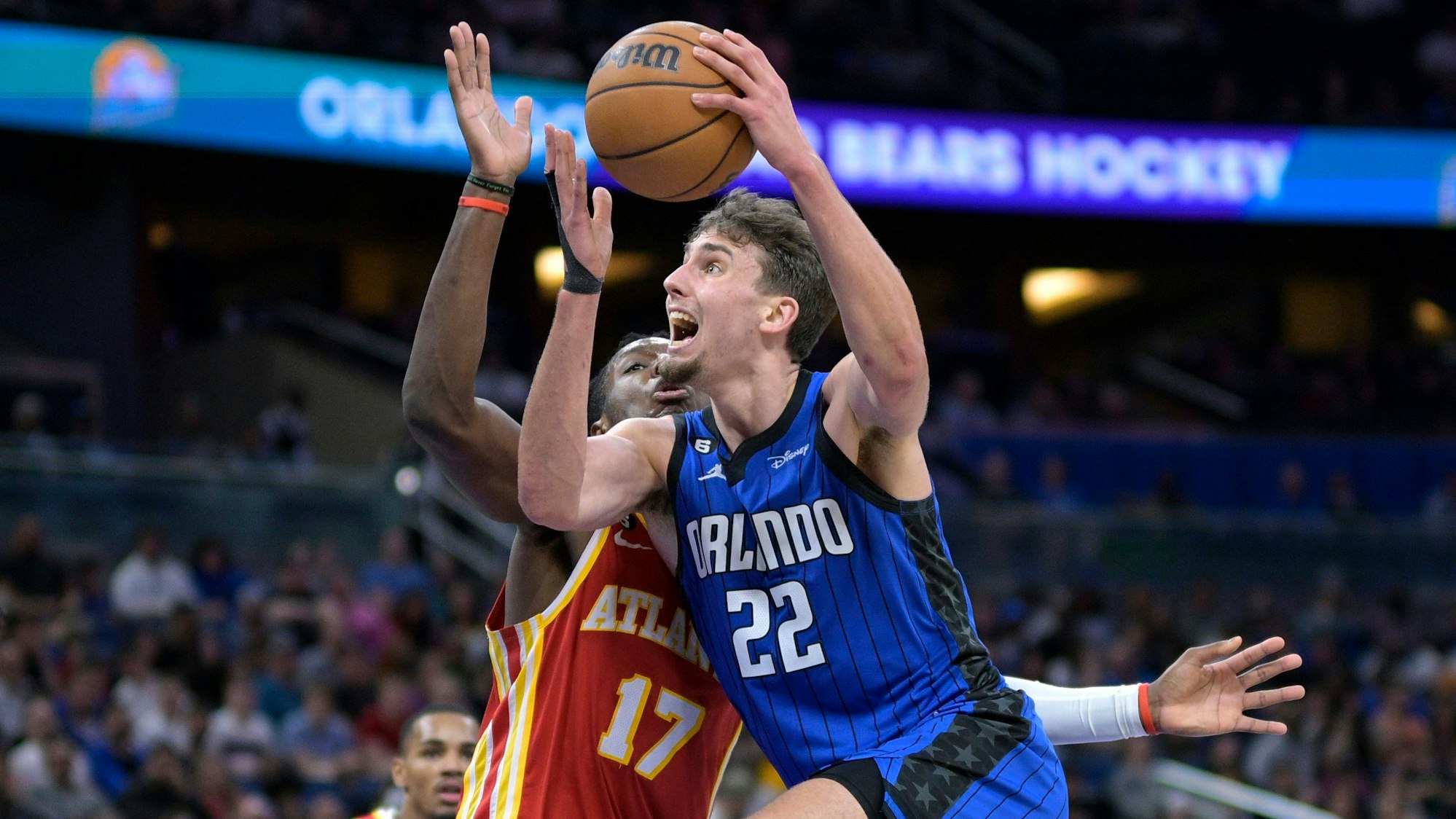 Franz Wagner steigt mit dem Basketball in der Hand zum Korb hoch. Gegenspieler Onyeka Okongwu von den Atlanta Hawks versucht, ihn im NBA-Spiel zu stoppen.