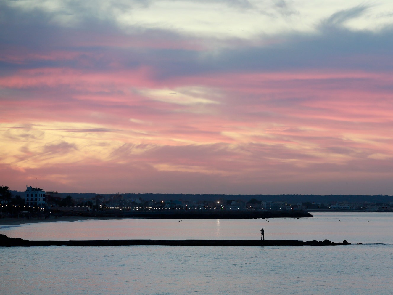 Ein Mann fotografiert mit seinem Mobiltelefon auf einer Mole an der Strandpromenade von Palma im September 2022 den Sonnenaufgang auf Mallorca.