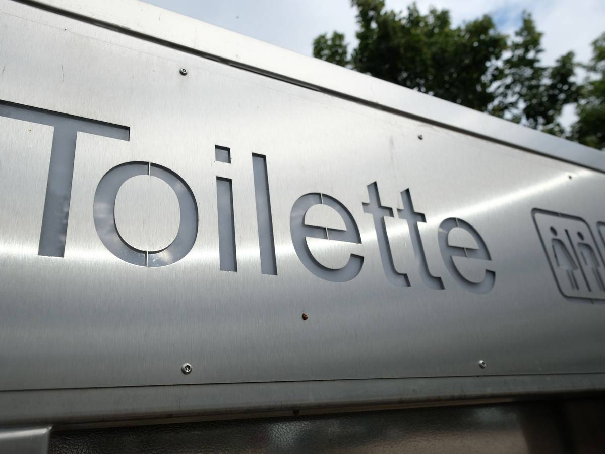 Ein Schild weist in der Innenstadt den Weg zu einer öffentlichen Toilette.