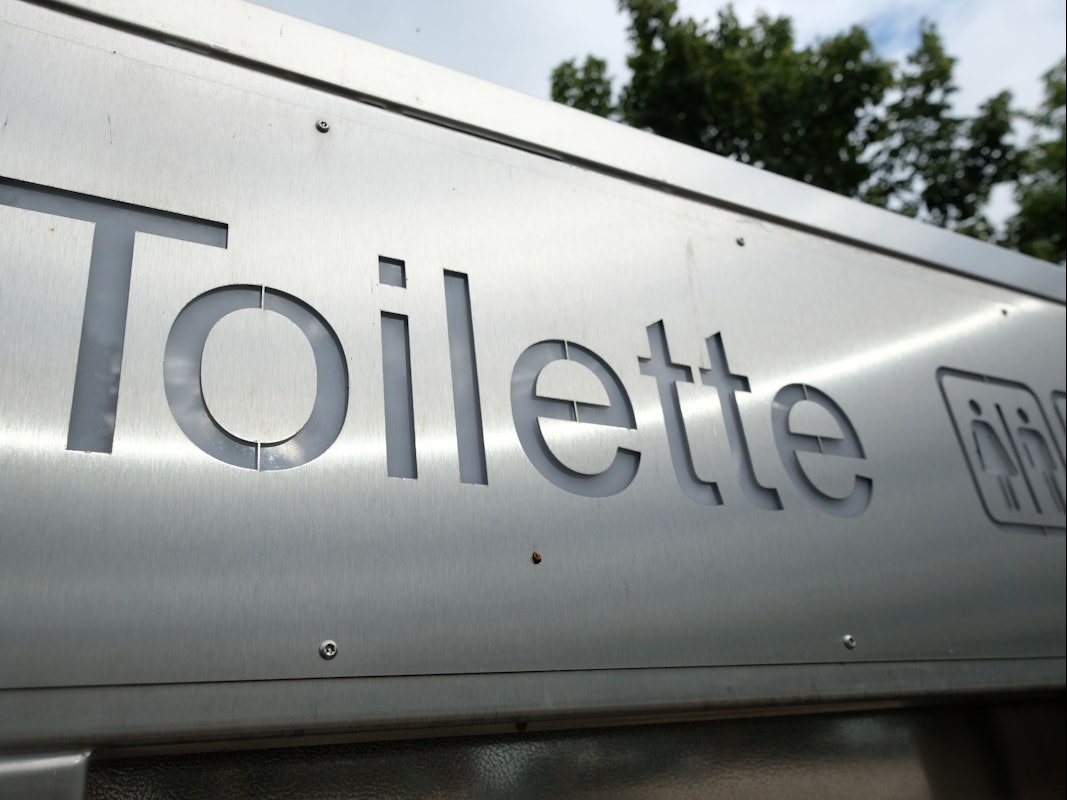 Ein Schild weist in der Innenstadt den Weg zu einer öffentlichen Toilette.