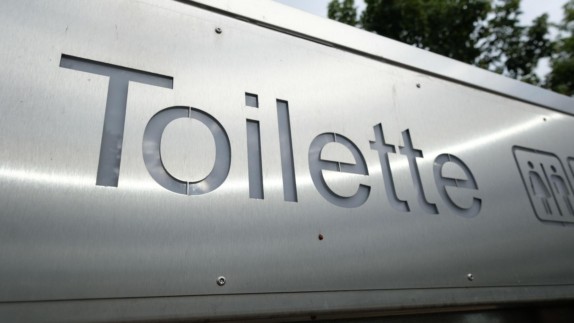 Ein Schild weist in der Innenstadt den Weg zu einer öffentlichen Toilette.